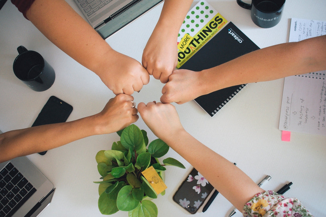 five fists bumping over office desk