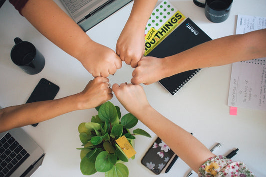 five fists bumping over office desk